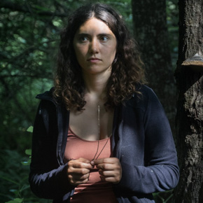 Frau im Wald mit Baumpilz im Hintergrund
